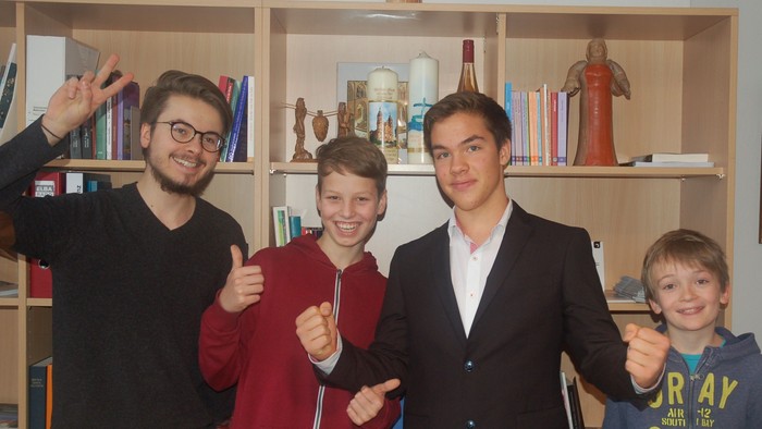 Vier Männer stehen vor Bücherregal
