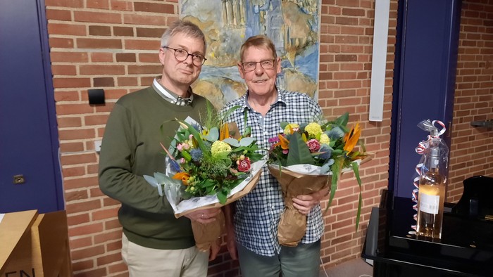 To mænd står sammen med blomsterstær i en køkkenmiljø