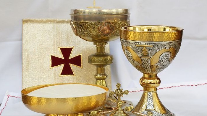 Goldene Kelche und Patene auf weißem Tuch