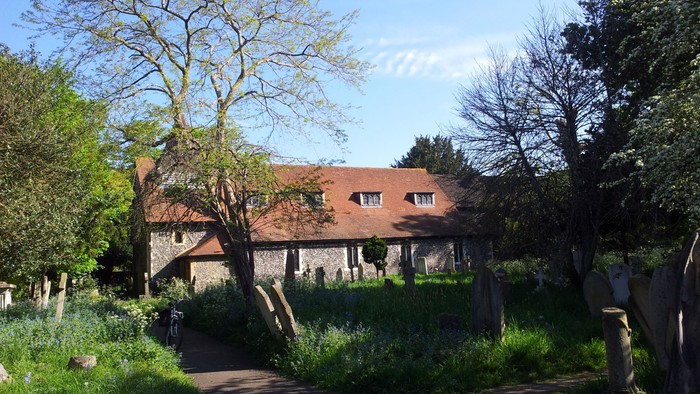 A quaint house with a thatched roof surrounded by lush greenery and trees.