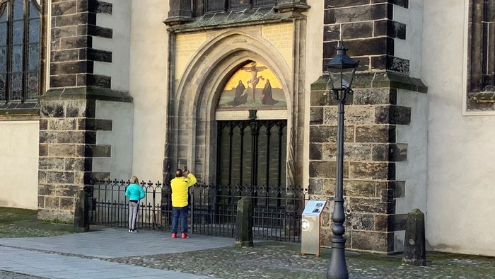 Gamle kirke med købebygning og to børn foran.