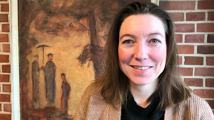Kvinde står foran maleri med to figurer.