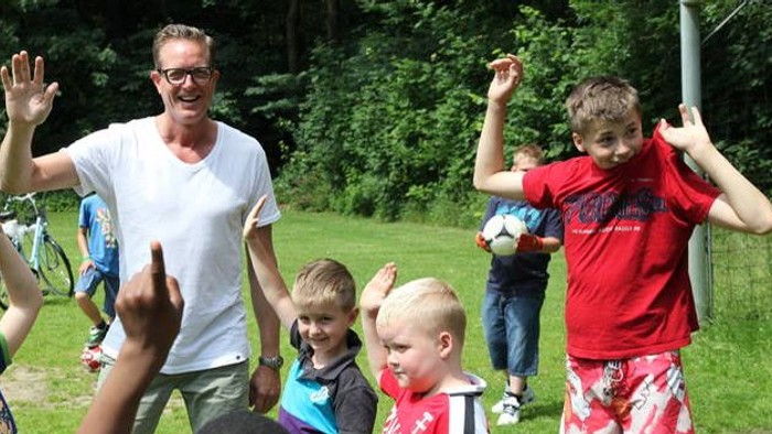 En mand og en gruppe børn spiller i en park.