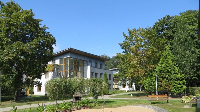 Das Bild zeigt ein großes Haus mit Garten und Sandfläche.