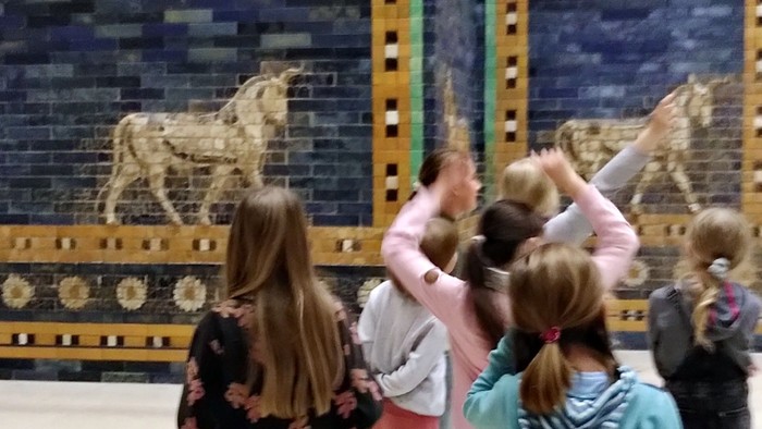 Kinder betrachten Wandgemälde mit goldenen Pferden in einem Museum.