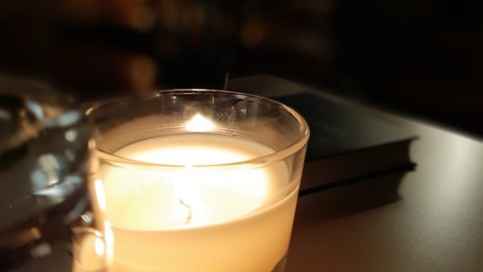 Eine brennende Kerze in einem Glas auf einem Tisch