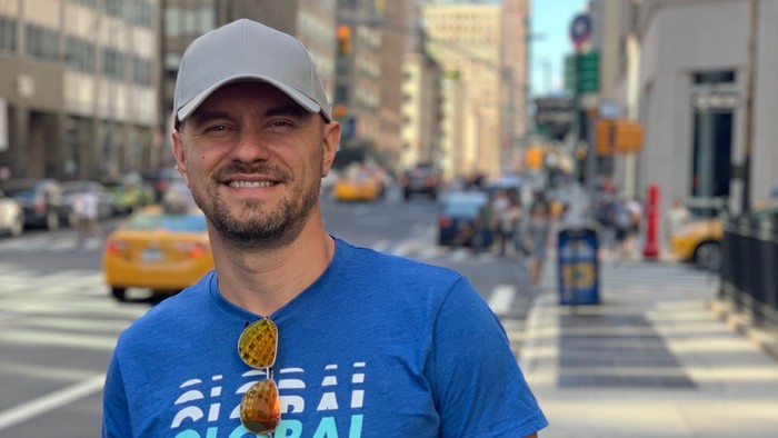 Mann in blauer T-Shirt mit Aufdruck "GLOBAL" auf belebter Stadtstraße