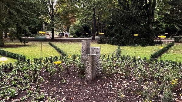 Drei Stelen auf rundem Grabfeld, mit kleinen, gelben Scheiben auf Stäben