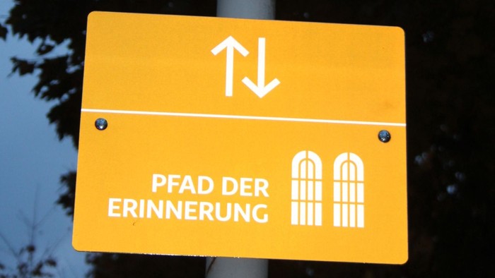 Warnschild mit Kindern und darunter Hinweisschild "Pfad der Frinnerung"
