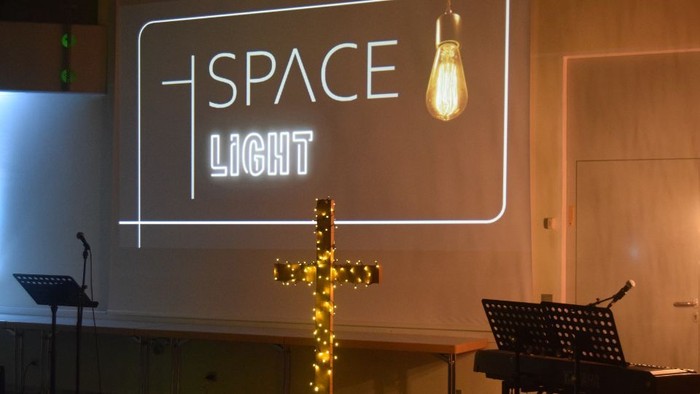 Leuchtendes Kreuz vor Neon-Schild "SPACE LIGHT"