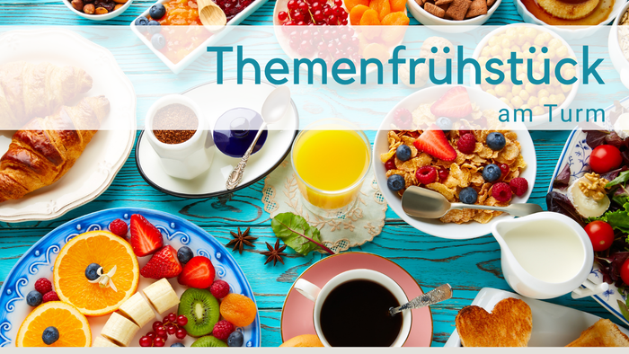 Hellblauer Holztisch mit Frühstückszutaten: O-Saft, Milchkännchen, obst, Cerealien, Tomaten, Croissant, Törtchen