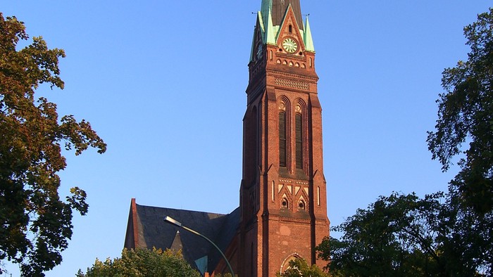 Hohe Kirchturmspitze mit goldener Spitze in klarem Blauhimmel