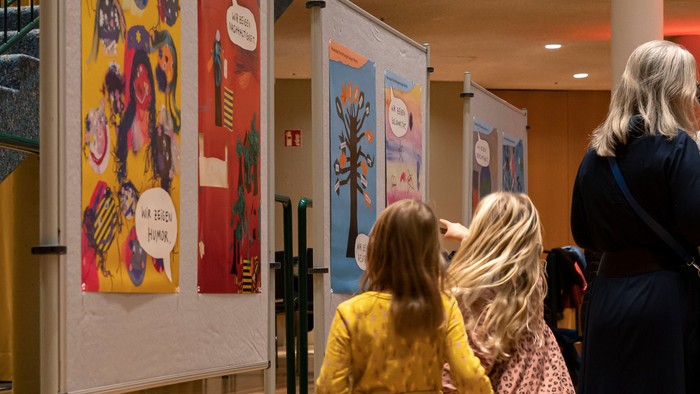 Kinder betrachten farbenfrohe Ausstellungsplakate in einem großen Raum