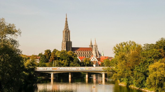 Gothische Kirche mit hohem Turm spiegeln sich im ruhigen Fluss
