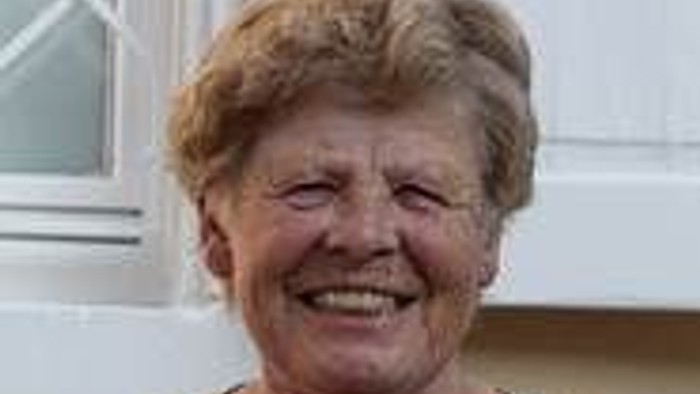 Eine ältere Frau mit kurzen, grauen Haaren lacht herzlich.