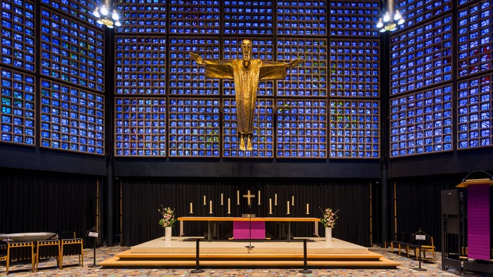 Die Kirche mit einem großen goldenen Kreuz und bunten Glasfenstern