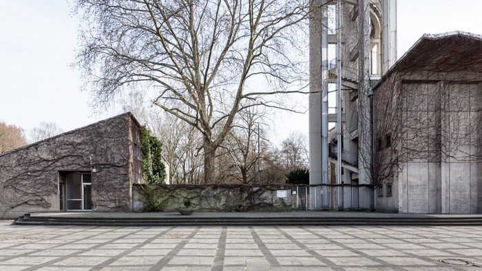 Ein moderner Gebäudekomplex mit großen Fenstern und einem kahlen Baum im Vordergrund