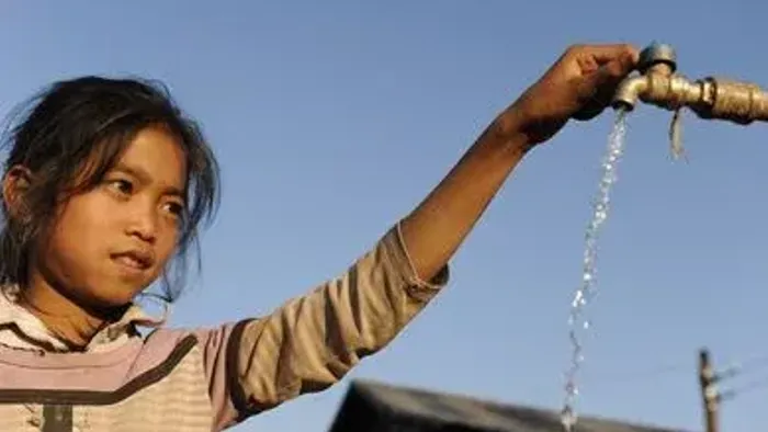 Ein Mädchen dreht einen Wasserhahn und lässt Wasser laufen.
