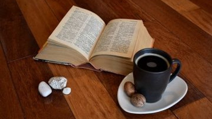 Offenes Buch und Tasse Kaffee auf Holzboden