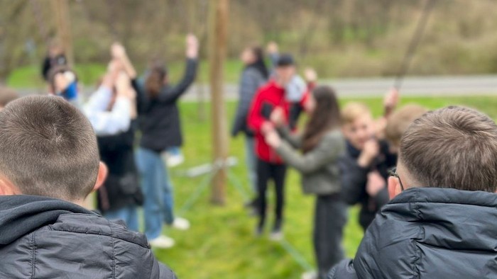 Eine Gruppe von Menschen spielt im Freien ein Spiel mit einem Seil.