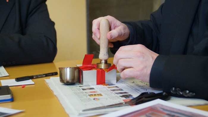 Mann stempelt Dokument ab, während er an Schreibtisch sitzt