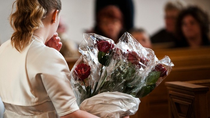 En kvinde holder en bundt røde roser i plastik.