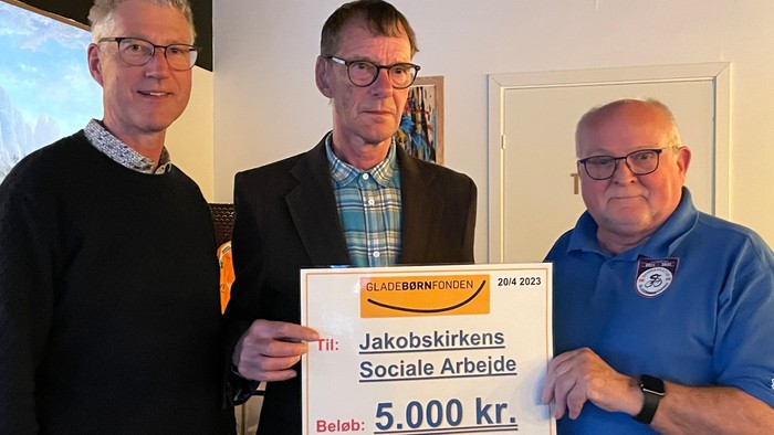 Tre mænd holder en stor sjekk på 5.000 kr. fra Jakobskirkenes Sociale Arbejde