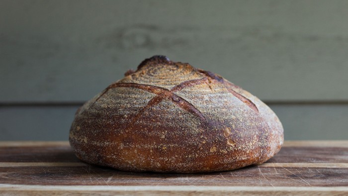 Ein frisches Brot liegt auf einem Holztisch.