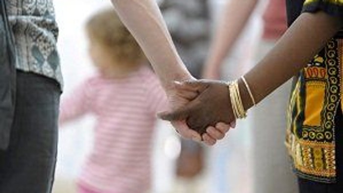 Two people holding hands, with a child in the background.