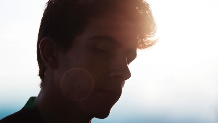 Ein Mann mit kurzem Haar im Gegenlicht, die Sonne scheint hell hinter ihm.