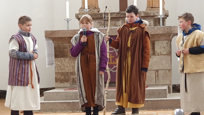 Vier Personen in historischen Gewändern stehen in einer Kirche.