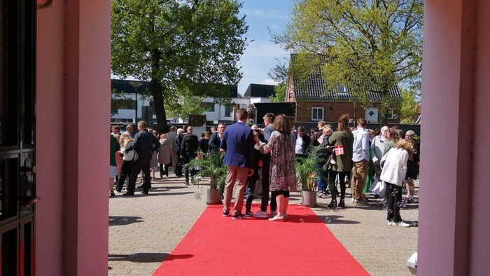 En rød teppich ved udflytning, hvor gæster går og snakker.