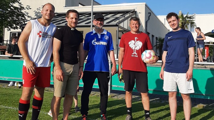 Fünf Männer stehen auf einem Fußballfeld