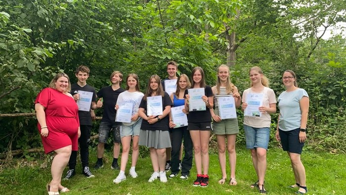 Eine Gruppe von Menschen hält Zertifikate in einem Park