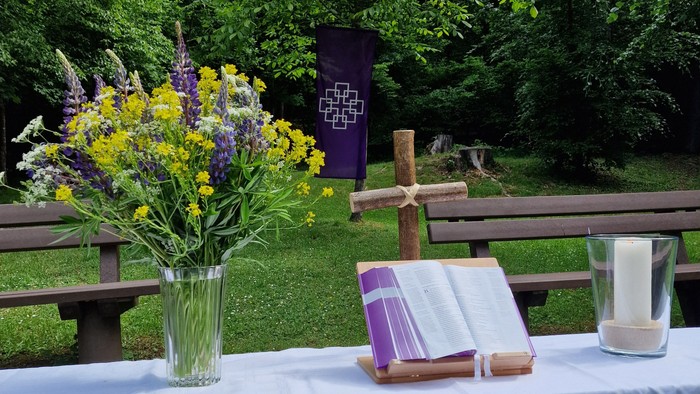 Ein Tisch mit Blumenstrauß, Bibel und Kerze im Freien