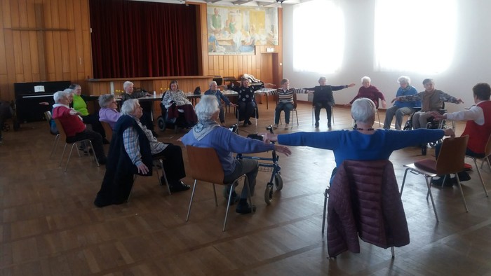 Seniorengruppe übt Tanzen in einem großen Saal
