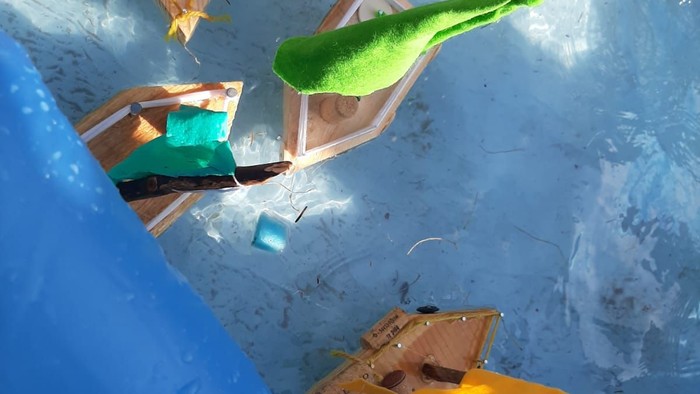 Kinder spielen mit selbstgebauten Booten im Wasser