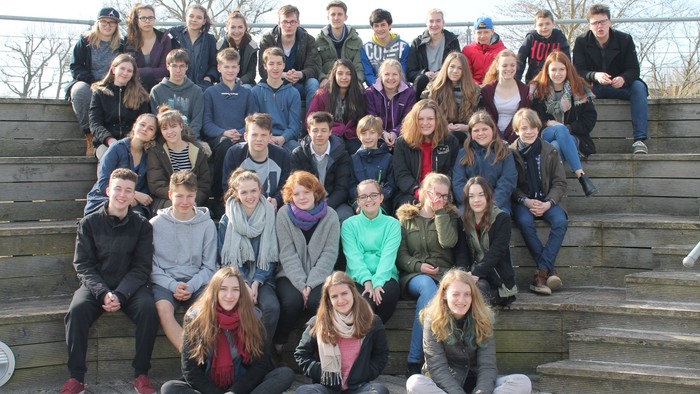 Eine Gruppe von Jugendlichen posiert auf Treppenstufen im Freien