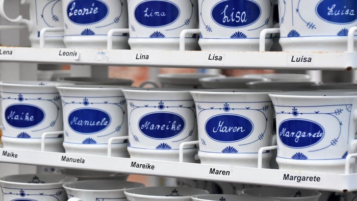 Mehrere blau-weiße Tassen mit persönlichen Namen auf Regalen