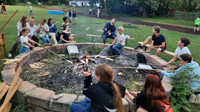 Eine Gruppe von Menschen sitzt um ein Lagerfeuer im Freien und genießt die Gesellschaft.