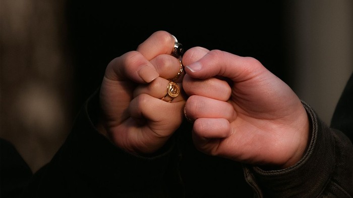 Zwei Hände halten einen kleinen Gegenstand, eine trägt einen Ring