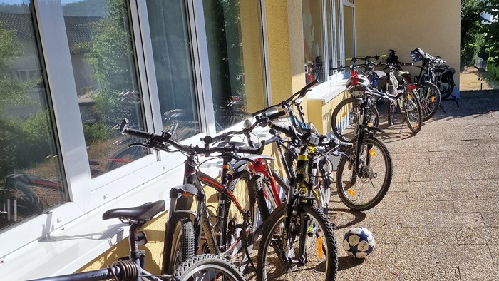 Eine Reihe von Fahrrädern steht vor einem gelben Gebäude mit großen Fenstern.