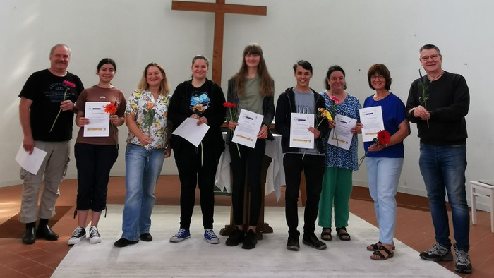Gruppe von Menschen in Kirche mit Urkunden vor Kreuz