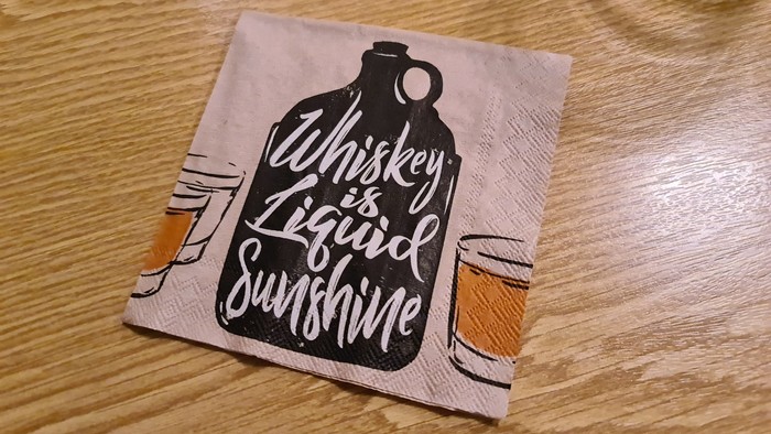 Das Bild zeigt ein T-Shirt mit einer Whiskey-Flasche und dem Spruch 