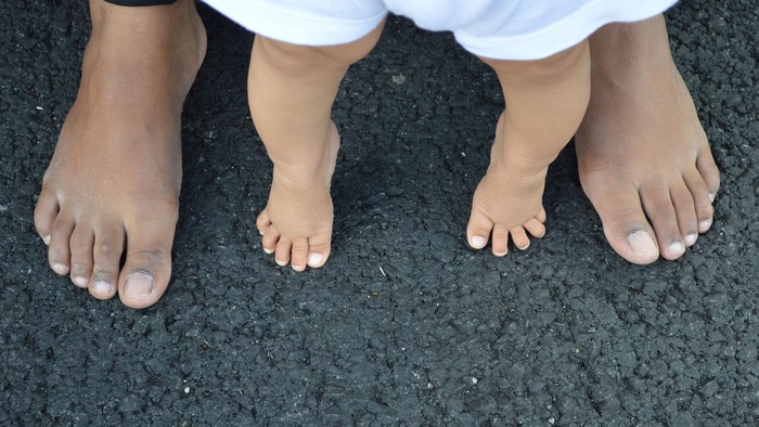 Zwei nackte Füße auf schwarzem Asphalt