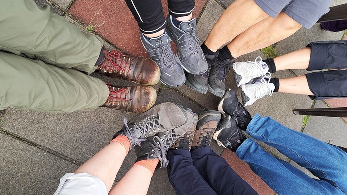 Eine Gruppe von Menschen steht im Kreis, ihre Schuhe sind zu sehen.