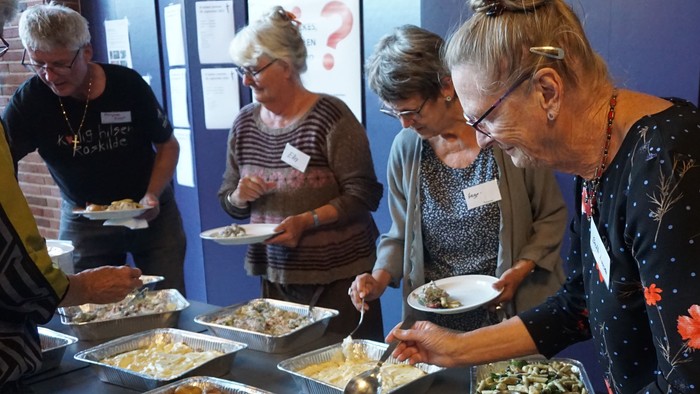 En gruppe mennesker serverer sig mad på en buffet.