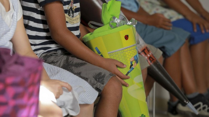 Ein Kind hält einen grünen Roboter, während es auf einem Stuhl sitzt.