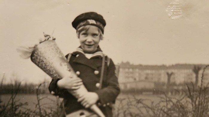 Ein Junge in Uniform hält eine Fackel und lächelt.