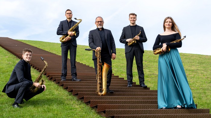 Fünf Musiker posieren mit Saxophonen auf Treppe